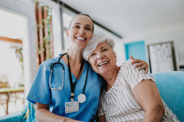 Compassionate healthcare - Smiling nurse in scrubs with elderly resident showing warmth and professional care